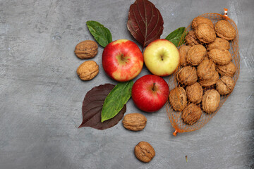 Red apples and autumn leaves on gray background. Top view, copy space