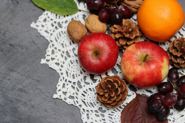 Autumn still life with apples, chestnuts and pine cones on dark background with space for text. 