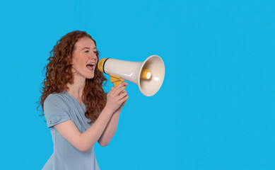 Young woman enthusiastically speaking into a megaphone against a vibrant blue background in a...