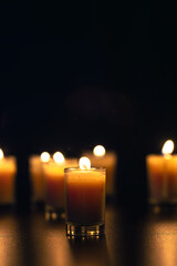 Burning candle on black background with backlight. Memorial Day.