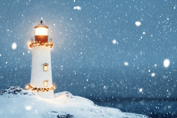 A serene winter scene featuring a lighthouse adorned with Christmas lights, glowing warmly amidst falling snow on a snowy coastal landscape.
