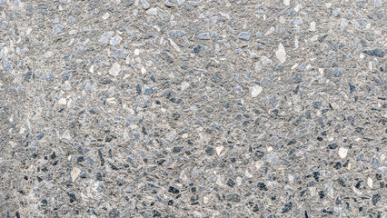 A close-up of a rough, textured concrete surface with visible small stones. Perfect for industrial, construction, and abstract design projects