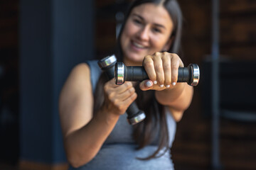 Pregnant woman in the gym with dumbbells in her hands.