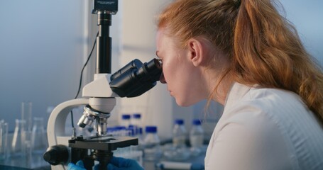 Medical science laboratory: Female biochemist looks under microscope, does analysis of sample, develops vaccine. Professional microbiologist, scientist uses high-tech equipment. Medicine. Close Up.