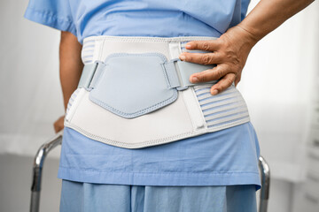 Asian lady patient wearing back pain support belt for orthopedic lumbar with walker.