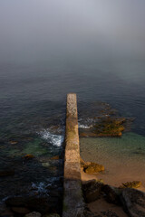  A long, narrow pier stretching into the misty ocean. Perfect for projects related to travel, nature, or solitude.