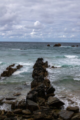 A dramatic seascape with crashing waves against a rocky breakwater, stretching towards the horizon. The stormy sky adds a sense of intensity to the scene.