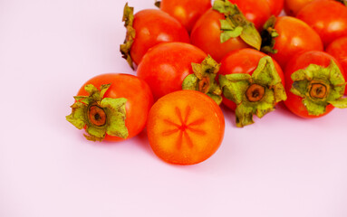 Persimmon fruits on pink background, copy space for text.