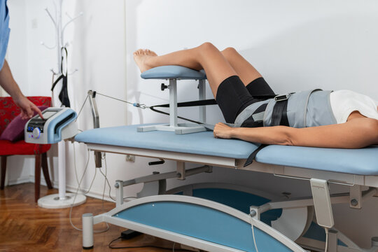Physical therapist uses mechanical traction to relieve back pain and stiffness by gently stretching the spine, reducing pressure, and enhancing mobility for improved recovery.