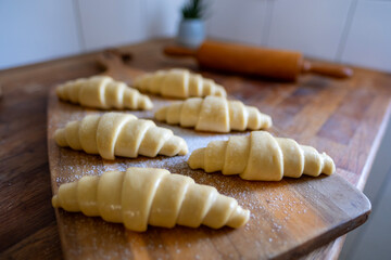 kitchen interior, Unbaked homemade flaky croissants on wooden board, prepared for oven, homemade pastry, baking preparation