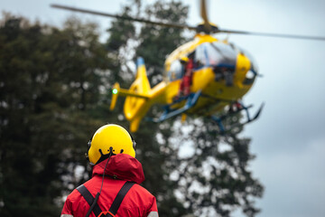 Rear view of paramedic against landing helicopter of emergency medical service. Themes rescue, help...