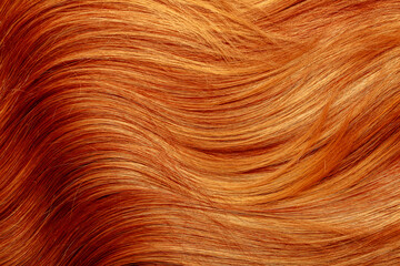 Red hair close-up as a background. Women's long orange hair. Beautifully styled wavy shiny curls....