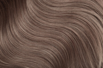 Blond hair close-up as a background. Women's long light brown hair. Beautifully styled wavy shiny...
