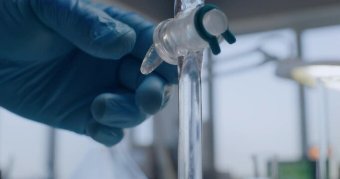 Advanced medical science laboratory: Close up of chemist opening stopcock on separating funnel, adding liquid. Professional scientist conducts chemical experiment using lab device. Chemistry concept.