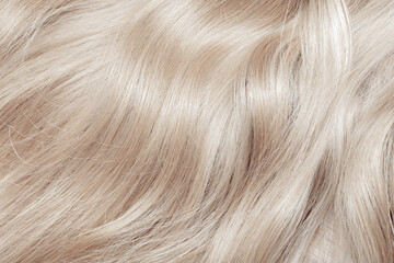 Blond hair close-up as a background. Women's long blonde hair. Beautifully styled wavy shiny curls....