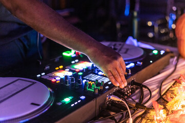 Skilled dj adjusts controls on a mixing console in a vibrant nightclub, creating the perfect sound...