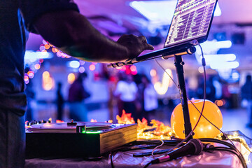 Dj is mixing music at a party using a laptop and a turntable, with people dancing in the...