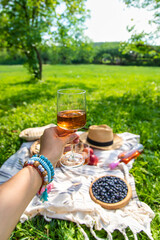 Wine in hands of woman at picnic. Selective focus.