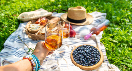 Wine in hands of woman at picnic. Selective focus.