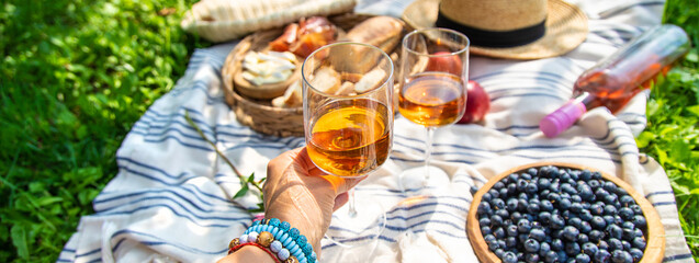 Wine in hands of woman at picnic. Selective focus.