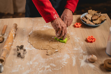 Christmas and New Year traditions concept. Christmas bakery in the kitchen. Man making gingerbread, cutting cookies of gingerbreads dough. Cooking process and family culinary