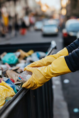 A volunteer in rubber gloves cleans up trash in the city. Volunteers Day