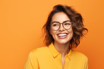 Portrait of happy smiling young woman in glasses, over yellow background