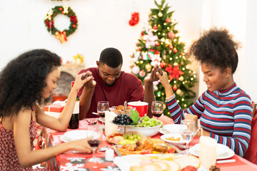 African family holding hands and praying on Thanksgiving or Christmas on holiday during dinner festive. People sharing time together at home