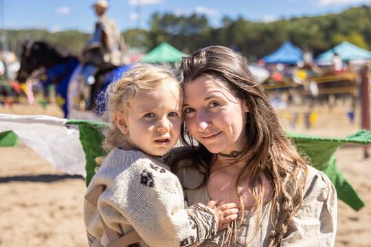 Mother holding her young son while enjoying a renaissance faire on a bright sunny day