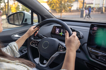 Young woman driving a car. Hands on the wheel. View from the back to the road.