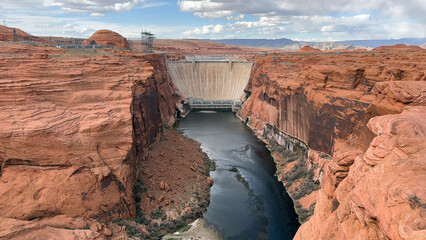 View of Glen Canyon Dam and the Colorado River from the overlook on Highway 89 in Page, Arizona, USA. Showcasing the impressive scale of the dam and the beauty of the surrounding red rock canyon.
