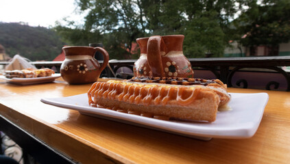 churros y cafe calientes en jarro con arboles y montaña al fondo