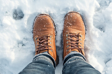 A close-up of the boots worn by an outdoor enthusiast standing in snow. 