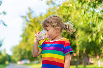 Fototapeta premium A child drinks water from a glass. Selective focus.