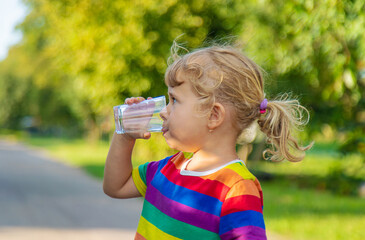 A child drinks water from a glass. Selective focus.