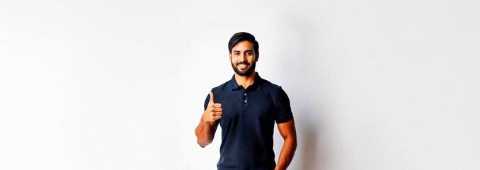 A South Asian man in a navy polo shirt giving a thumbs up against a white background.