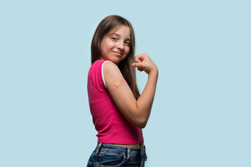 Young girl proudly flexing arm with bandage after vaccination