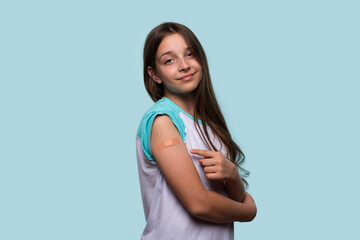 Girl points to bandage on arm after receiving vaccination.