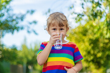 A child drinks water from a glass. Selective focus.