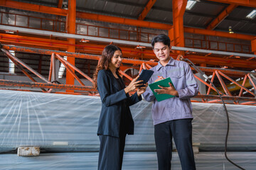 Female manager or inspector is checking or examining the quality control of metal sheet industry or factory with a professional male engineer employee, production quality control in metal warehouse.