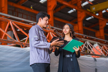 Female manager or inspector is checking or examining the quality control of metal sheet industry or factory with a professional male engineer employee, production quality control in metal warehouse.