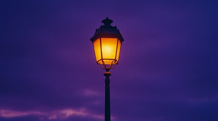 A single, illuminated street lamp stands tall against a purple twilight sky.