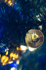 Bitcoin coin on christmas tree with bokeh lights. Finance concept.