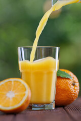 orange juice pouring into glass on table outdoors