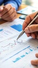 Hands analyzing financial data on paper, focusing on graphs and statistics for business insights and strategic decisions.