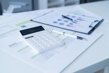 Calculator is sitting on top of financial reports, suggesting a businessman is analyzing the data and preparing a financial strategy