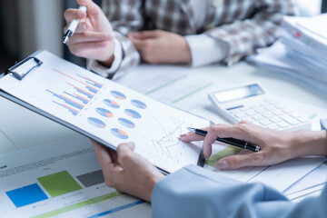 Two businesswomen analyzing financial data during a meeting in a professional office setting, collaborating and planning investments as a team