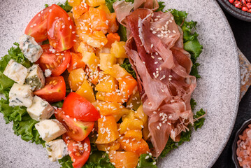 Appetizing salad with prosciutto, pumpkin, cheese and tomatoes