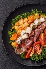 Appetizing salad with prosciutto, pumpkin, cheese and tomatoes