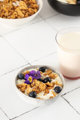 A healthy nutritious breakfast of natural Greek yoghurts, granola and fresh berries on tile background.